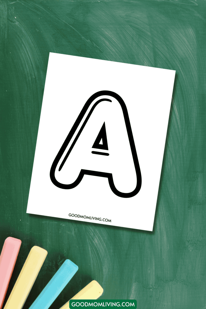 A printable sheet with the letter 'A' in bold, black outline on a green chalkboard background, accompanied by pieces of colored chalk in pink, yellow, and blue. The text "GOODMOMLIVING.COM" is at the bottom of the sheet.