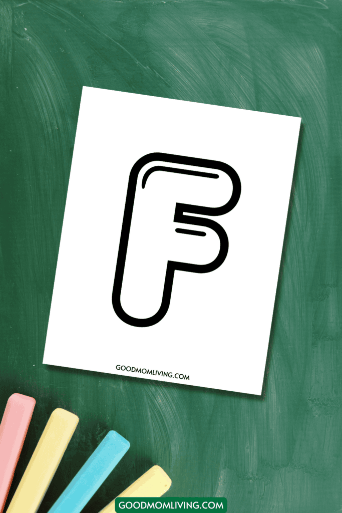 A white sheet of paper with a stylized black letter 'F' on it, placed on a green chalkboard with colorful chalks nearby.