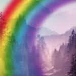 A vibrant rainbow arches over a tranquil landscape with a lake in the foreground and misty, forested mountains in the background.