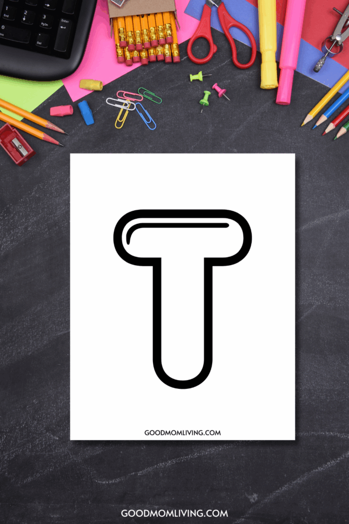 A black outlined letter 'T' on a white sheet of paper surrounded by assorted school supplies including pencils, paper clips, scissors, and highlighters on a chalkboard surface.